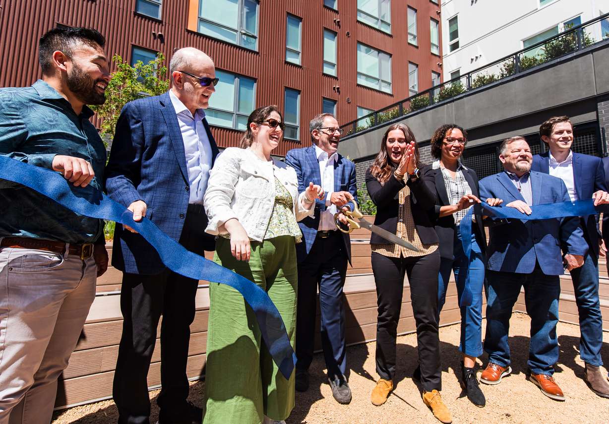 David Brint, founding principal of Brinshore Development, center, cuts a ribbon to signal the opening of Spark Apartments in Salt Lake City on Wednesday.