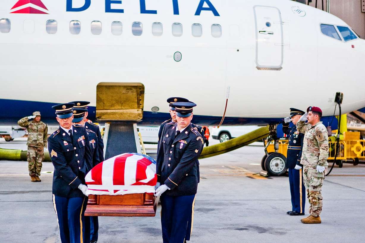 Military members in Utah respectfully carry a deceased veteran with honor before full military honors at a funeral.
