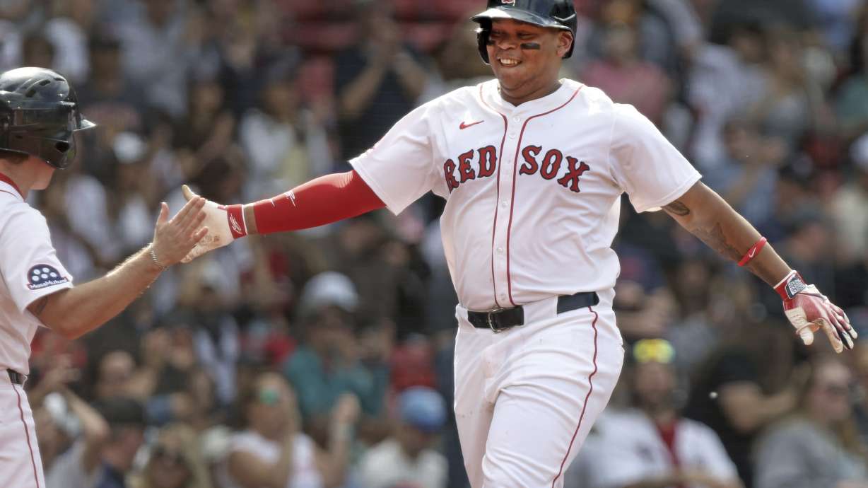 Boston Red Sox's Rafael Devers, right, is all smiles as he heads to the dugout after after hitting a home run during the seventh inning of a baseball game against the Texas Rangers, Thursday, May 8, 2025, in Boston.