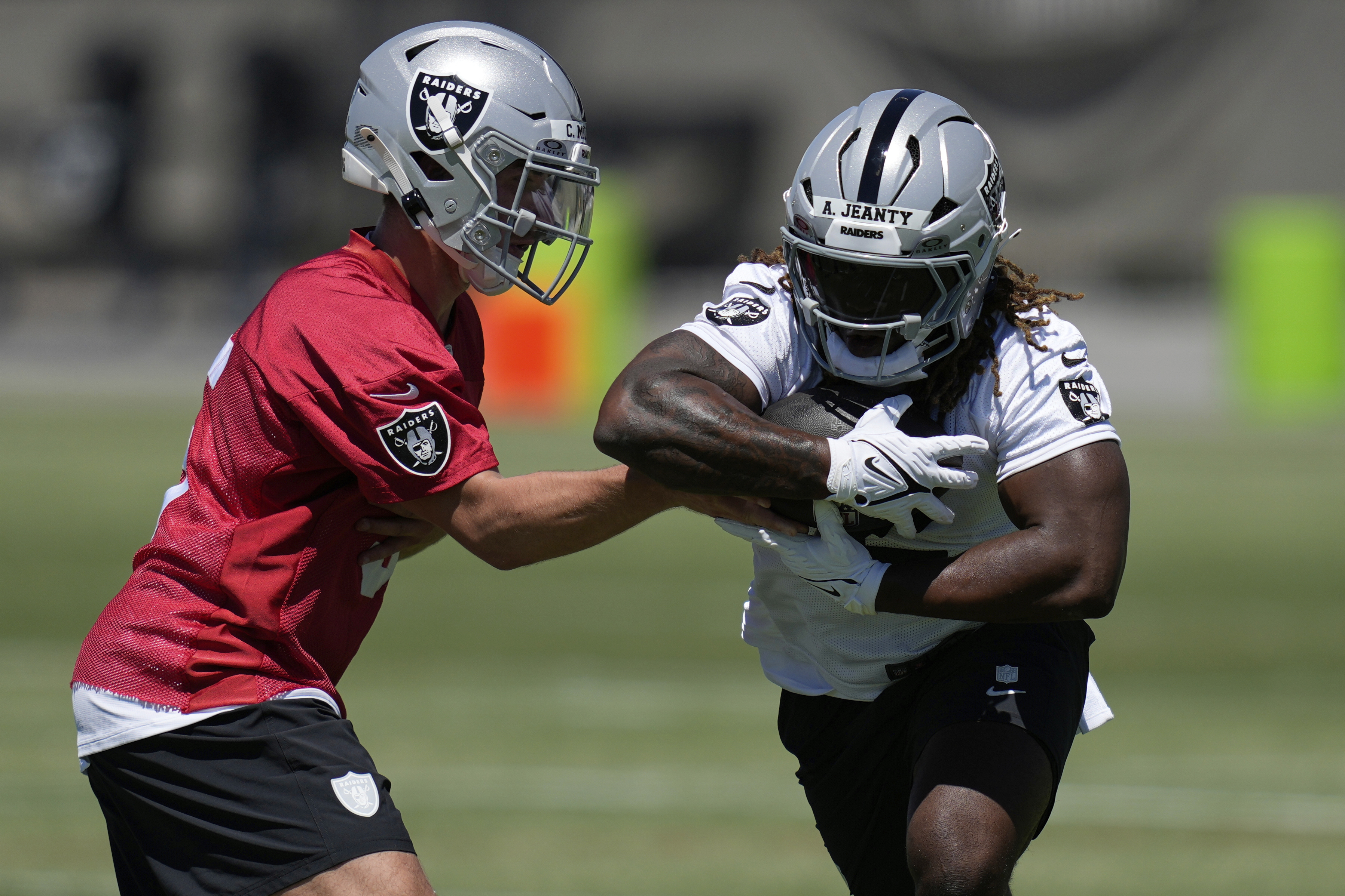 Las Vegas Raiders' quarterback Cam Miller hands off a ball to Ashton Jeanty during an NFL football rookie mini camp Friday, May 9, 2025, in Henderson, Nev.