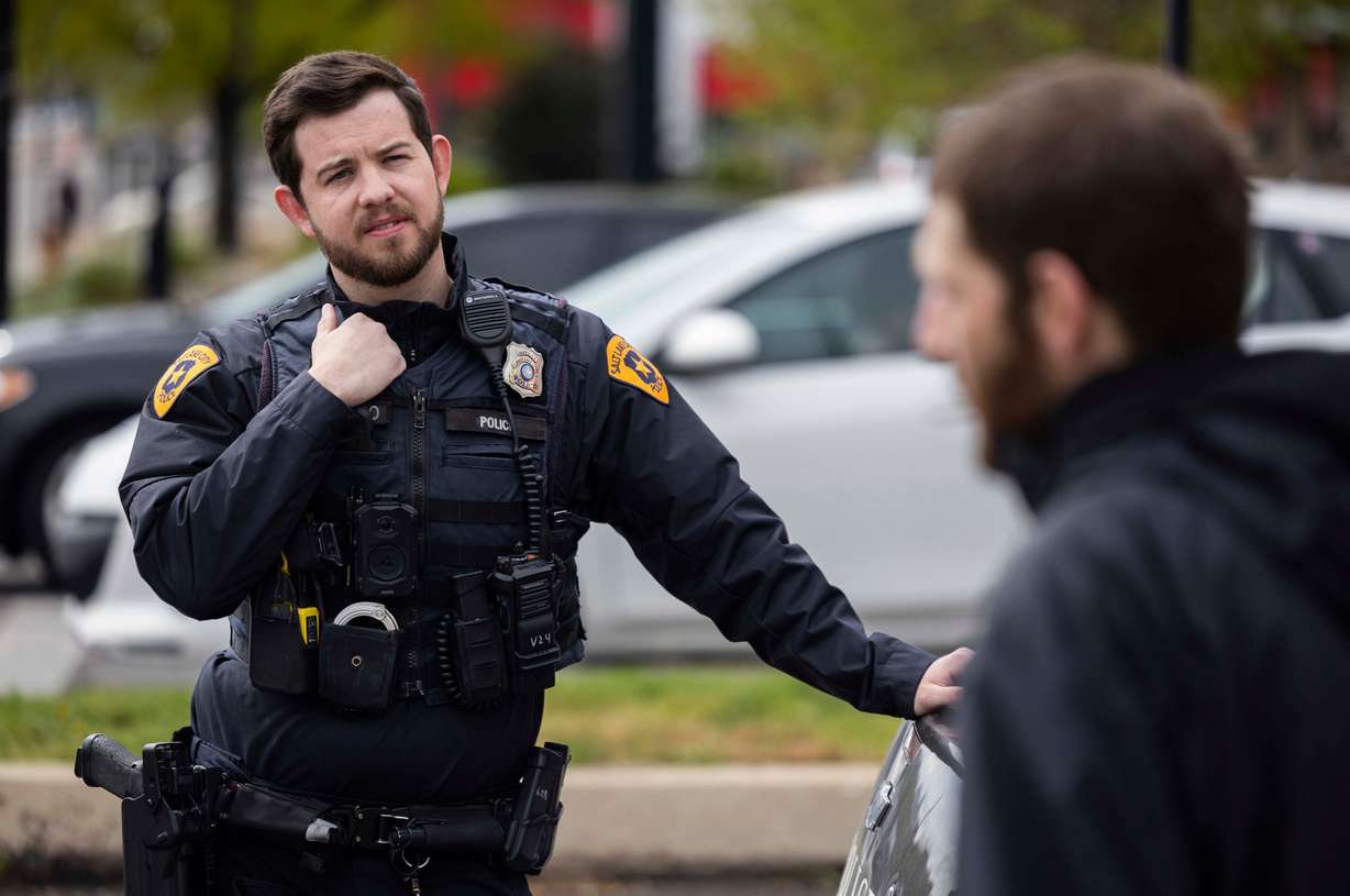 Salt Lake City police officer Michael Donahoo performs a wellness check on a man who was sleeping on the grass in Salt Lake City on April 17.