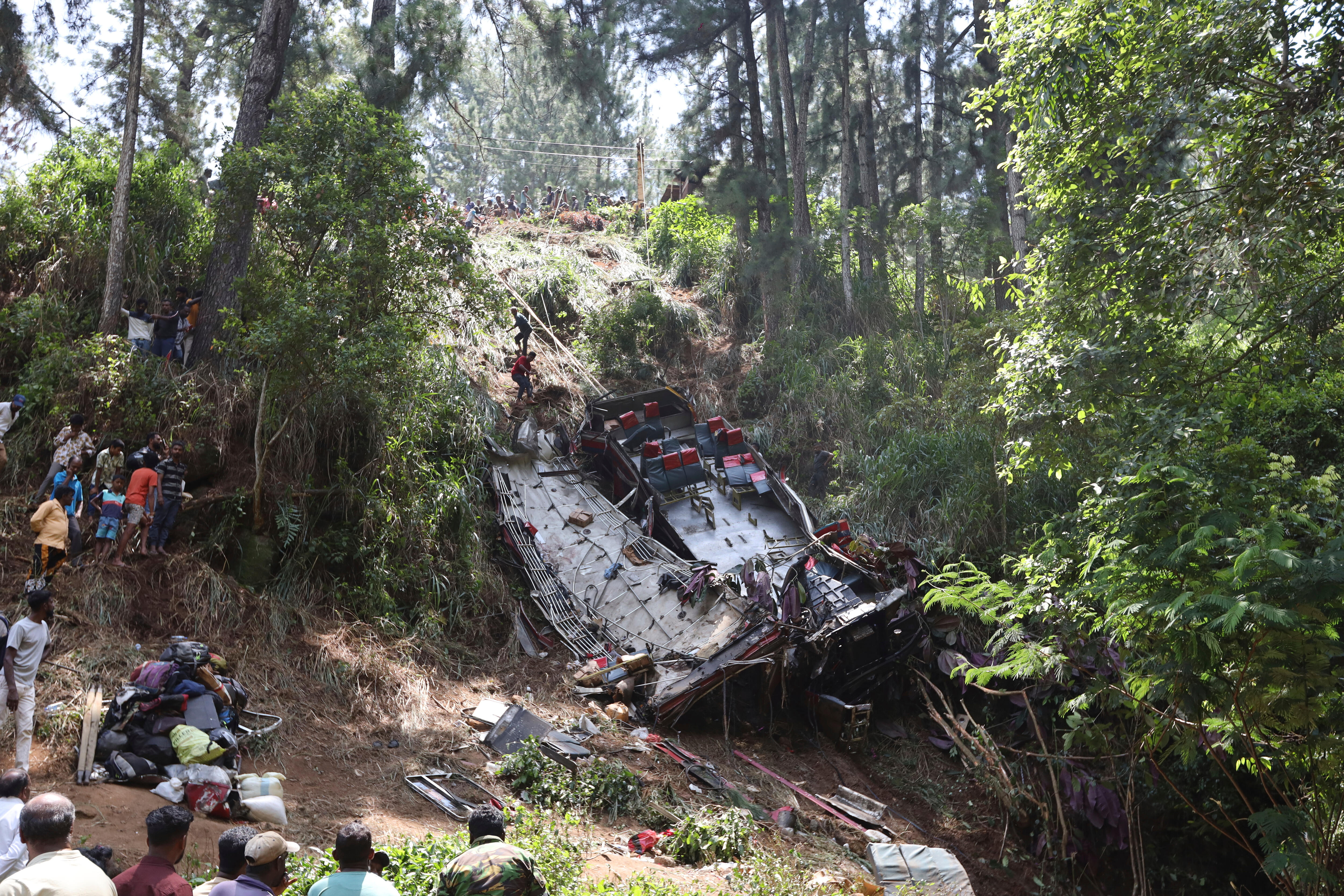 Onlookers watch as rescue workers search the debris at the site of a bus crash near the town of Kotmale, Sri Lanka, Sunday.