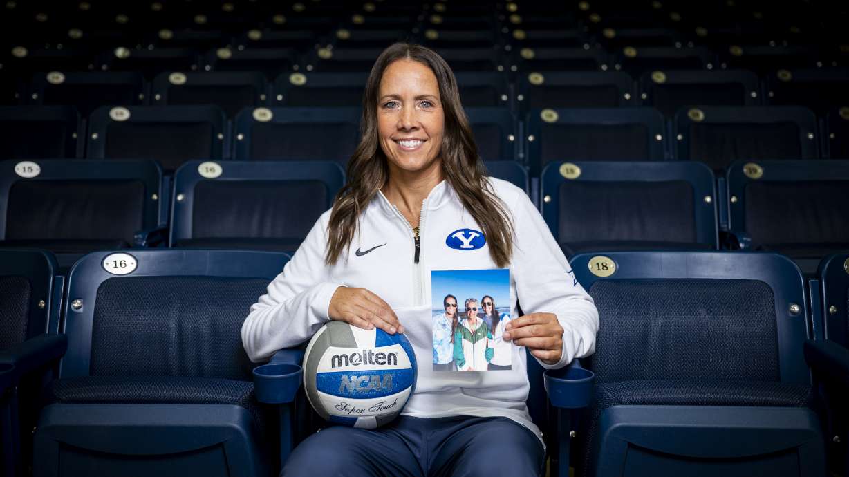 Brigham Young University women's volleyball head coach Heather Olmstead poses for a portrait while holding a photo of herself, her mother, Trudy Olmstead, and her twin sister, Nicole Hopkins, at Smith Fieldhouse on the campus of BYU in Provo on Friday, May 9, 2025.