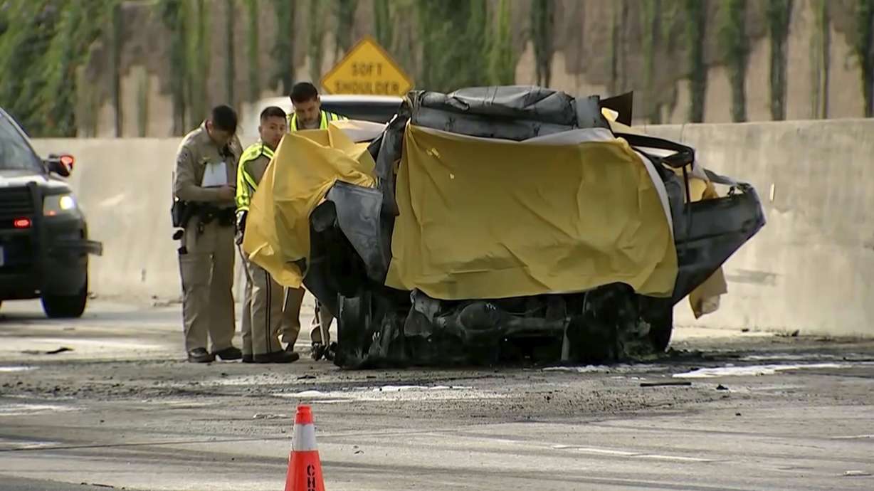 Police work near a crashed sport utility vehicle after it collided with a tour bus, Sunday in Los Angeles.