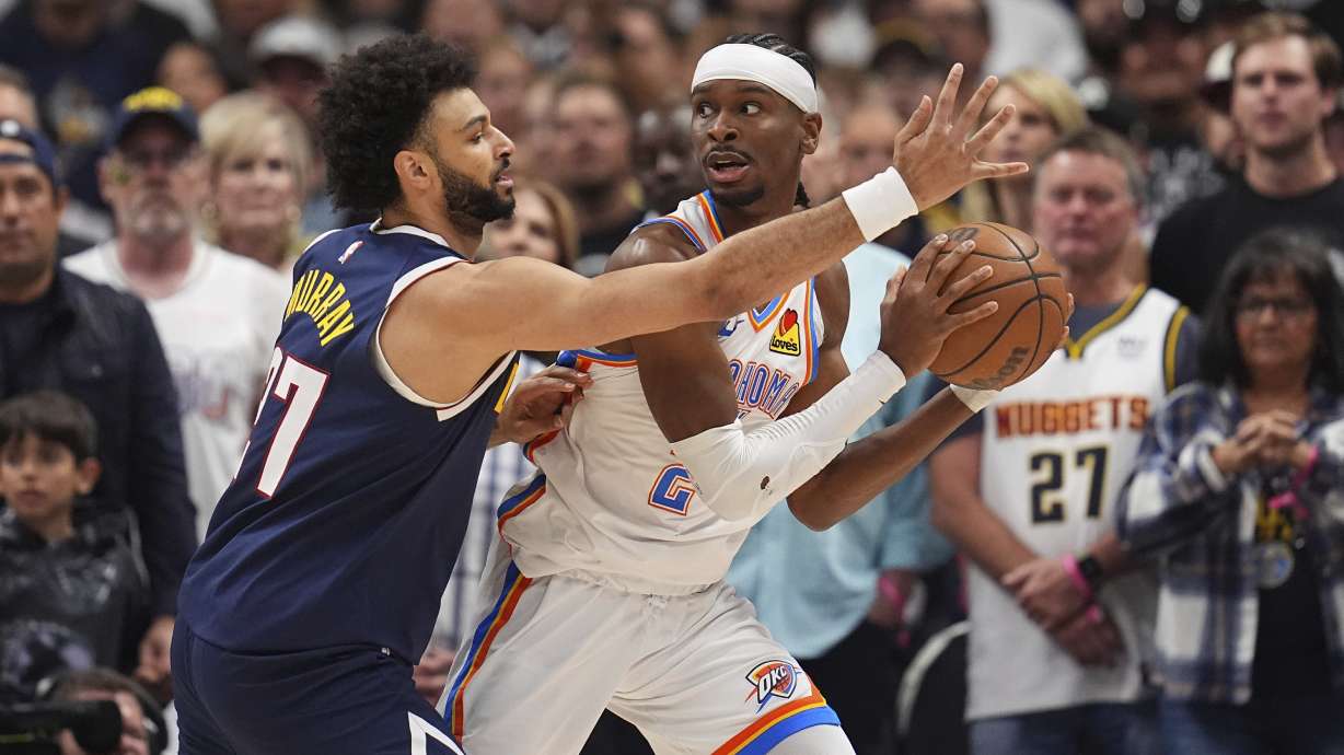 Oklahoma City Thunder guard Shai Gilgeous-Alexander, right, looks to pass the ball as Denver Nuggets guard Jamal Murray, left, defends in the first half of Game 4 in the Western Conference semifinals of the NBA basketball playoffs Sunday, May 11, 2025, in Denver.