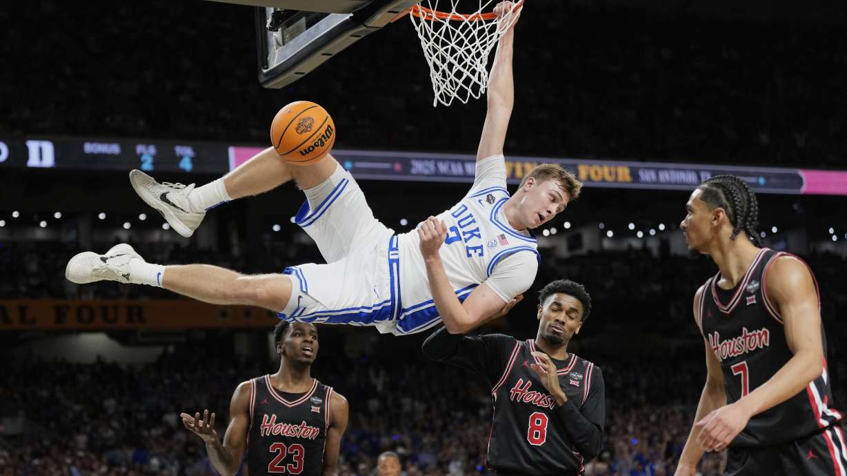 FILE - Duke's Cooper Flagg (2) looks back after dunking the ball as Houston's Terrance Arceneaux (23), Mylik Wilson (8) and Milos Uzan (7) watch during the first half in the national semifinals at the Final Four of the NCAA college basketball tournament, Saturday, April 5, 2025, in San Antonio.