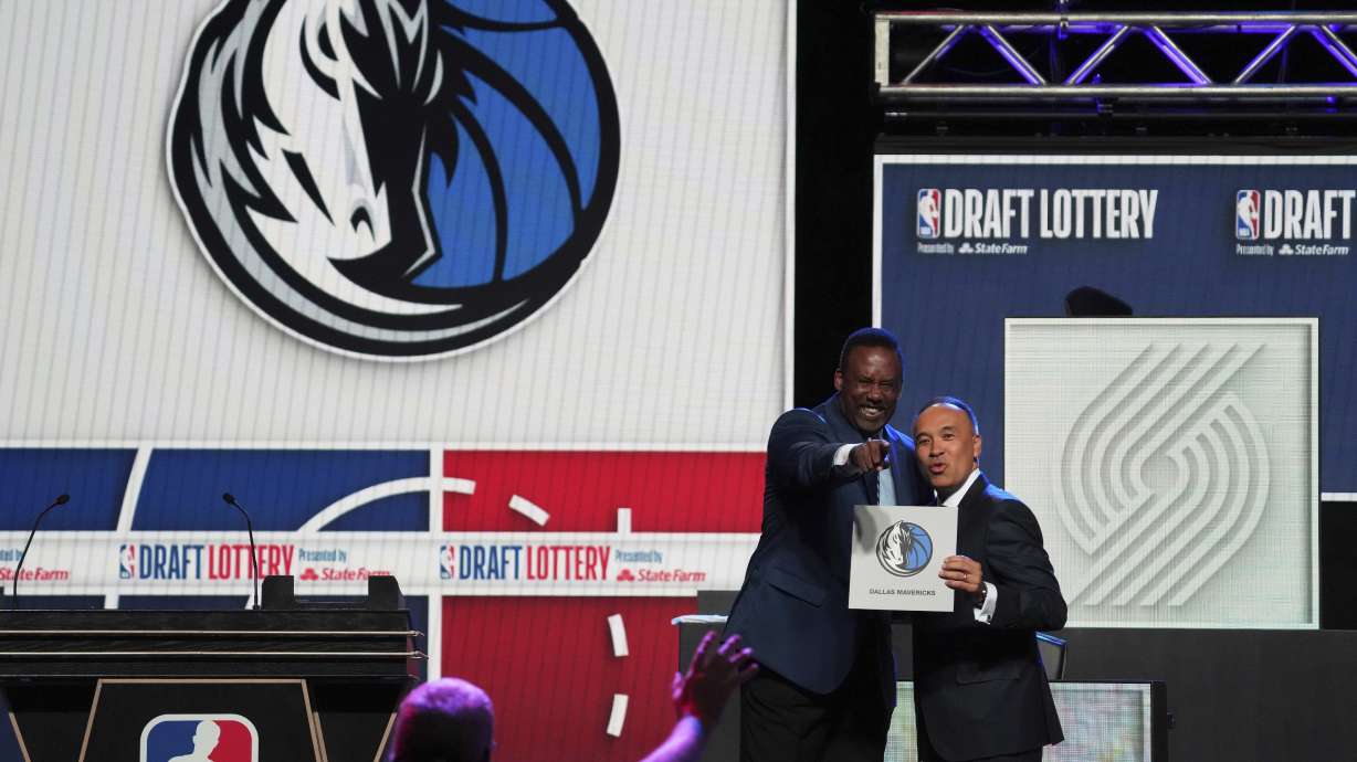 Dallas Mavericks' Rolando Blackman, left, and NBA Deputy Commissioner Mark Tatum, right, pose for photos after Tatum announced that the Mavericks had won the first pick in the NBA basketball draft lottery in Chicago, Monday, May 12, 2025.
