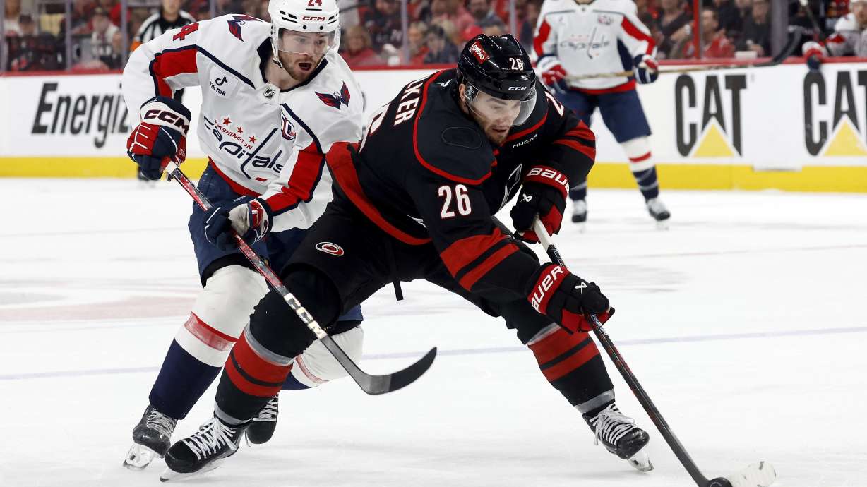 Carolina Hurricanes' Sean Walker (26) controls the puck in front of Washington Capitals' Connor McMichael (24) during the first period of Game 4 of a second-round NHL hockey playoff series in Raleigh, N.C., Monday, May 12, 2025.