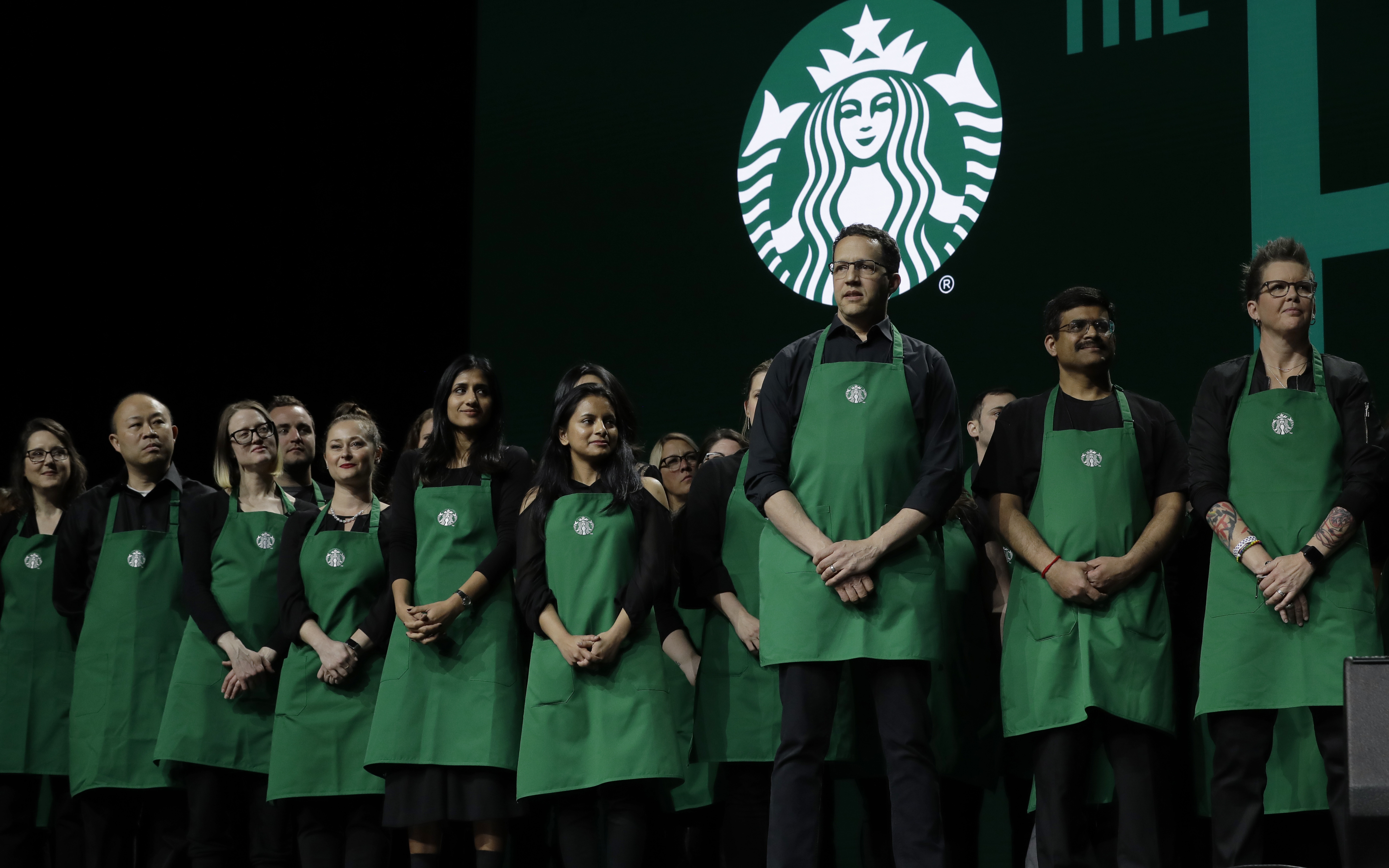 Starbucks baristas stand on stage, March 20, 2019, during an annual shareholders meeting in Seattle. Over 2,000 baristas are striking over the company's new dress code.