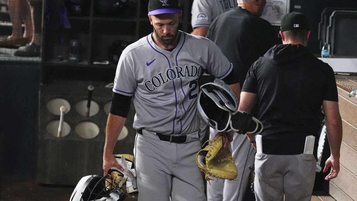 Colorado Rockies catcher Jacob Stallings (25) carries his gear as he walks from the dugout at the end of a baseball game against the Texas Rangers, Wednesday, May 14, 2025, in Arlington, Texas.