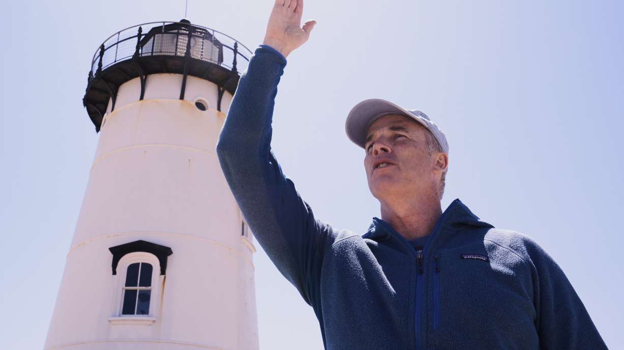 Endurance swimmer Lewis Pugh gestures to where he will begin his swim around Martha's Vineyard island, which is expected to take 12 days, near the Edgartown Lighthouse, Monday, May 12, 2025, in Edgartown, Mass.