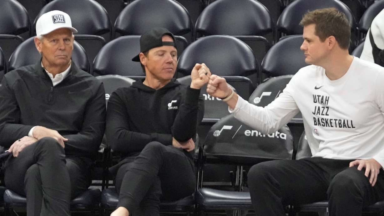Utah Jazz's CEO, Danny Ainge, left, looks on as Jazz owner Ryan Smith and head coach Will Hardy fist bump while sitting court side before the start an NBA basketball game against the Oklahoma City Thunder Tuesday, Feb. 6, 2024, in Salt Lake City.