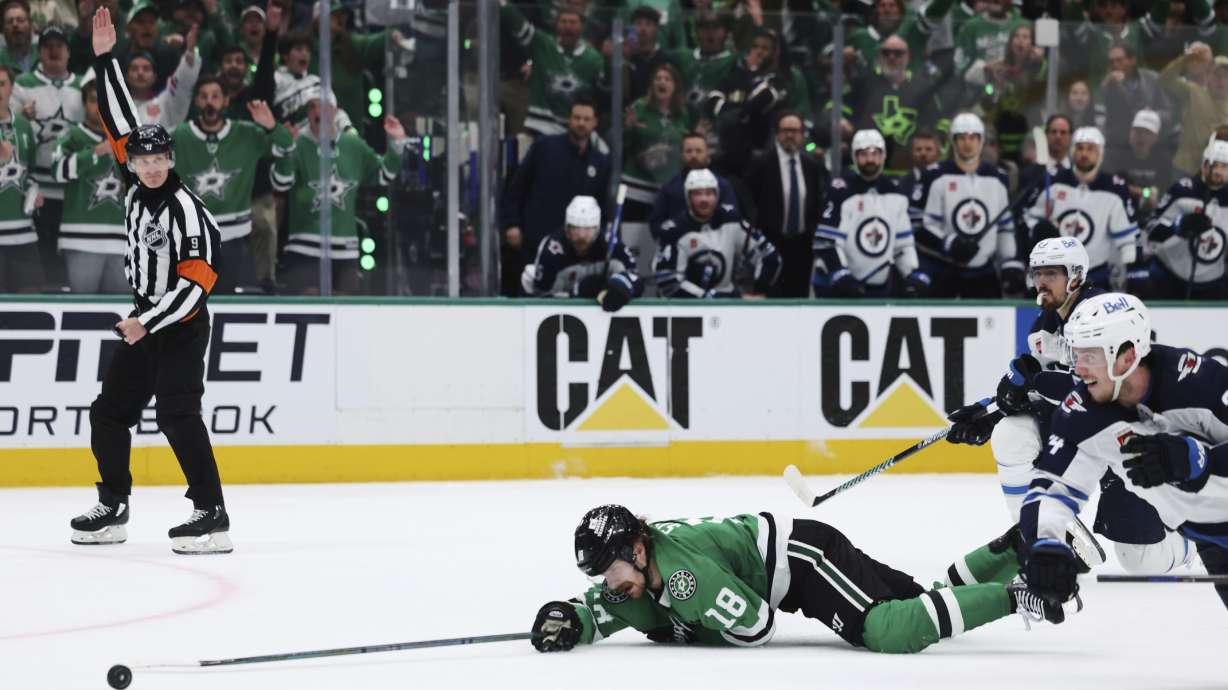 Dallas Stars center Sam Steel (18) is tripped by Winnipeg Jets' Mark Scheifele, right rear, on an attack in the third period of Game 6 of a second-round NHL hockey playoff series in Dallas, Saturday, May 17, 2025.