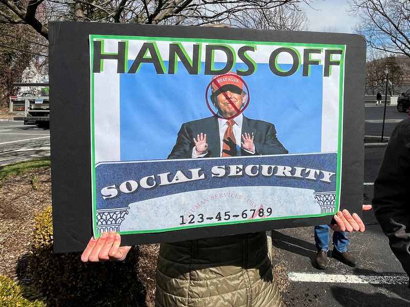 A person holds a sign during a protest against the Trump administration's cuts to Social Security in White Plains, N.Y., March 22. The Supreme Court Friday permitted DOGE access to Social Security data while a legal challenge continues.