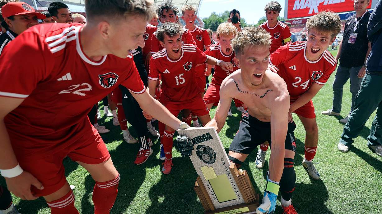 American Fork’s Ben Hess (#22) and goalkeeper Jackson Dingus hold the team trophy as American Fork runs with it towards the crowd to celebrate winning the boys 6A state soccer championship game against Bingham at America First Field in Sandy on Thursday, May 22, 2025. American Fork won 1-0.