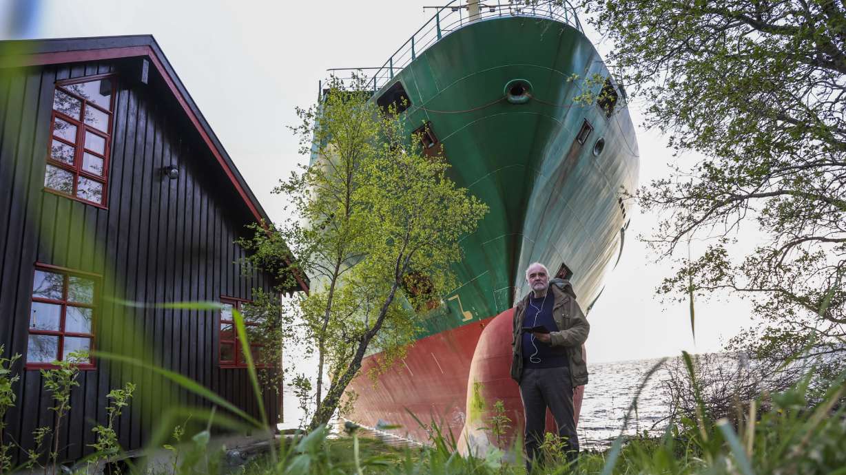 Johan Helberg stands next to his house, with the container ship NCL Salten in the background, after the 135-meter-long ship ran aground in Trondheim, Norway, Thursday.