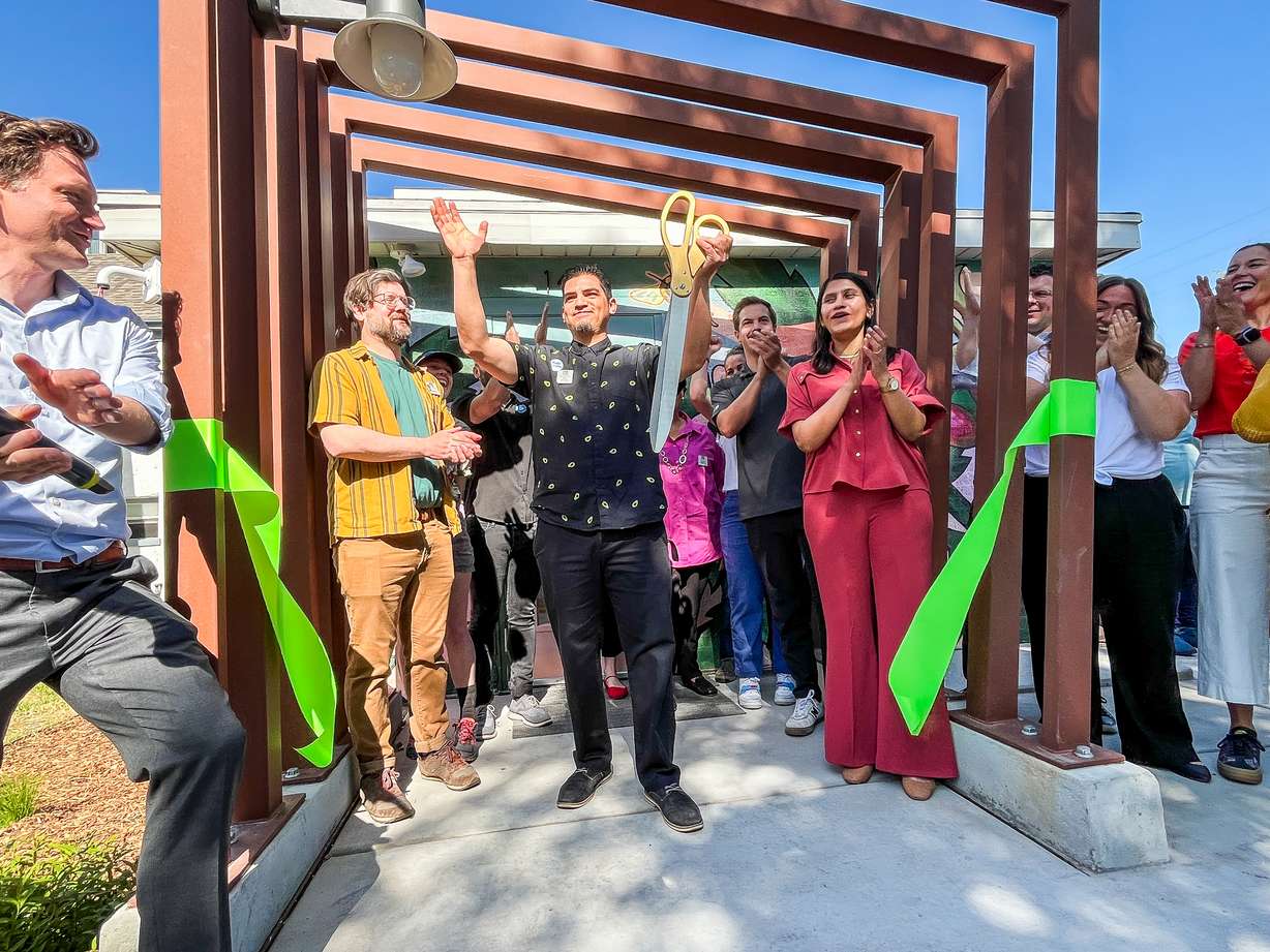 Xris Macias, manager of the Ballpark Library Lab, celebrates alongside city and community dignitaries after cutting a ribbon to open the new Salt Lake City building on Friday.