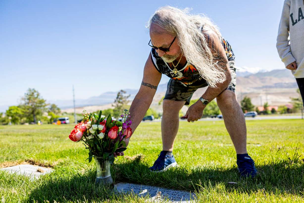 Kerry Rasmussen, of Clearfield, adjusts flowers on the grave of his mother and father at the Utah Veterans Cemetery and Memorial Park in Bluffdale on Wednesday.