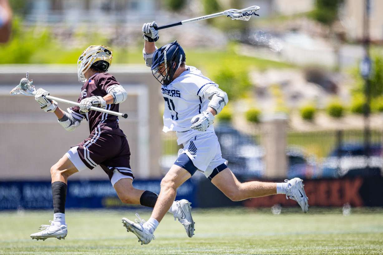Davis Darts midfielder Max Lifferth (5) runs with the ball as Corner Canyon Chargers midfielder Michael Wheatley (21) defends during the 6A boys lacrosse state championship at Zions Bank Stadium in Herriman on Friday, May 23, 2025.