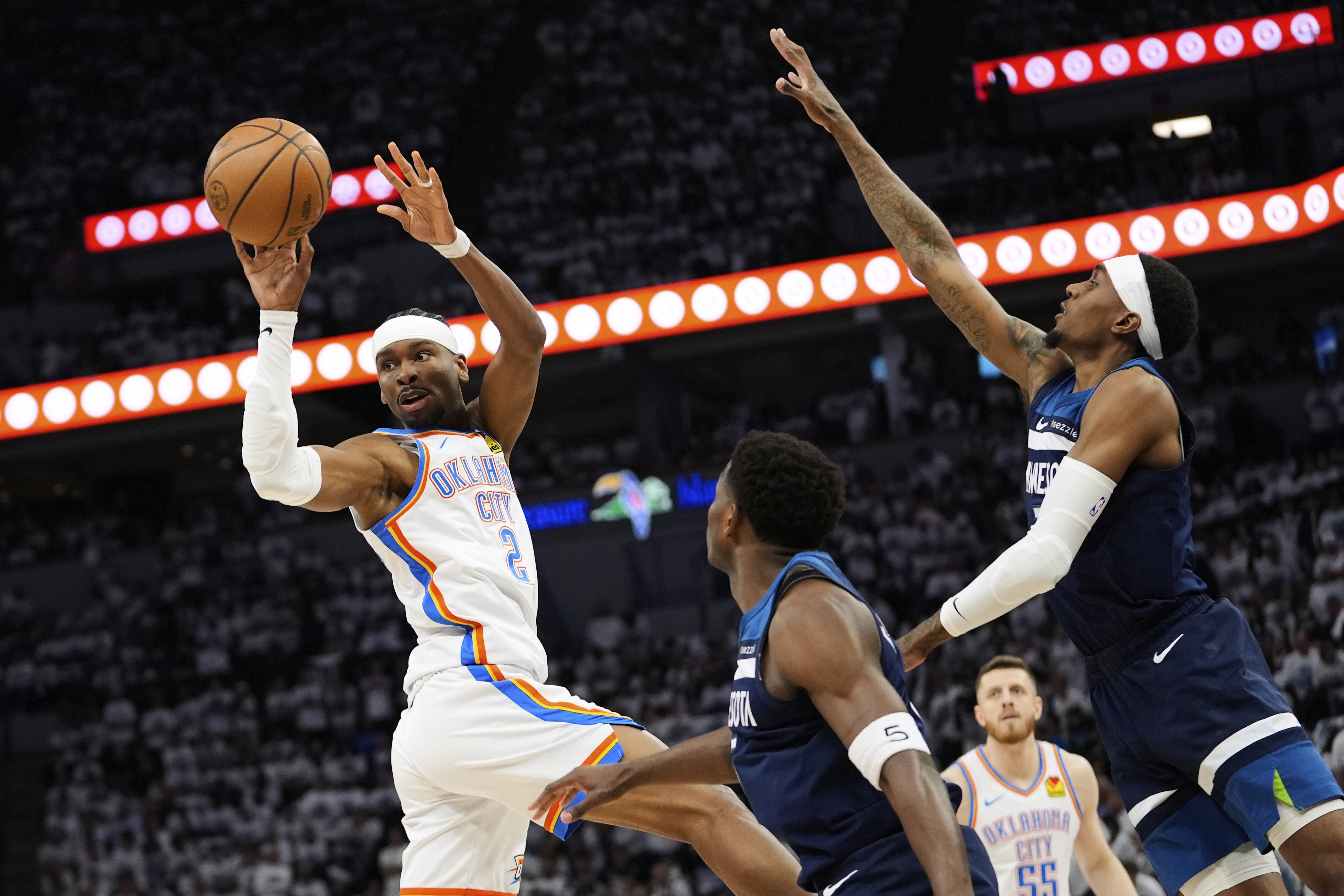 Oklahoma City Thunder guard Shai Gilgeous-Alexander (2) passes against Minnesota Timberwolves guard Anthony Edwards, center, and forward Jaden McDaniels, right, during the first half of Game 3 of the Western Conference finals of the NBA basketball playoffs, Saturday, May 24, 2025, in Minneapolis. 