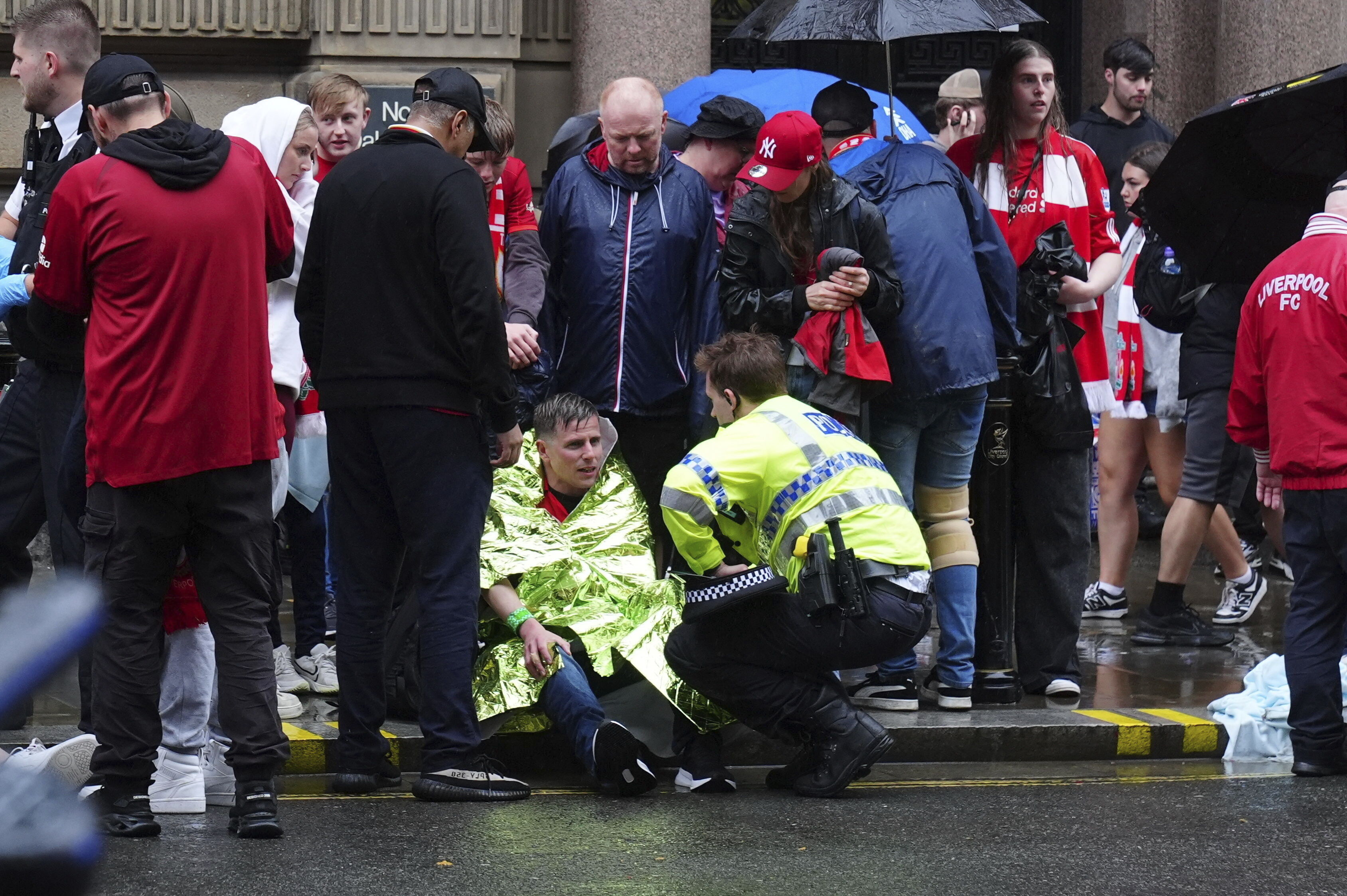 A police officer speaks with a man at the site of an incident on Water Street near the Liver Building in Liverpool after a car collided with pedestrians during the Premier League winners parade, in Liverpool, England, Monday May 26, 2025. 