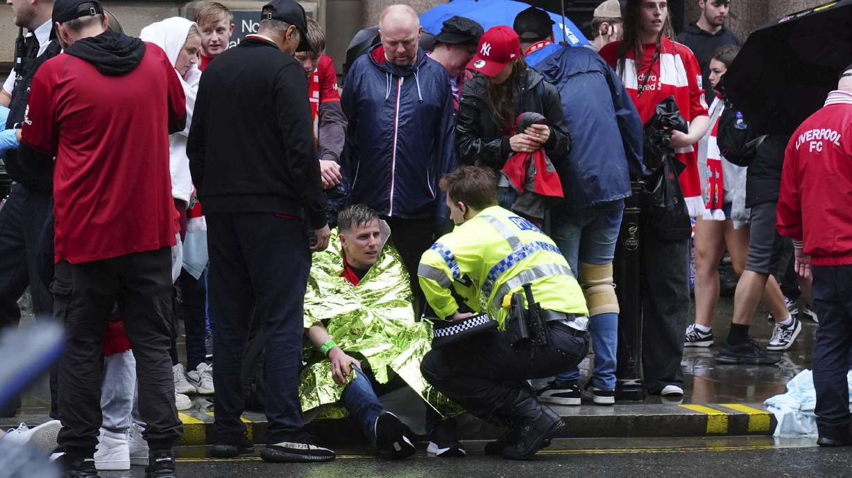 A police officer speaks with a man at the site of an incident on Water Street near the Liver Building in Liverpool after a car collided with pedestrians during the Premier League winners parade, in Liverpool, England, Monday May 26, 2025.