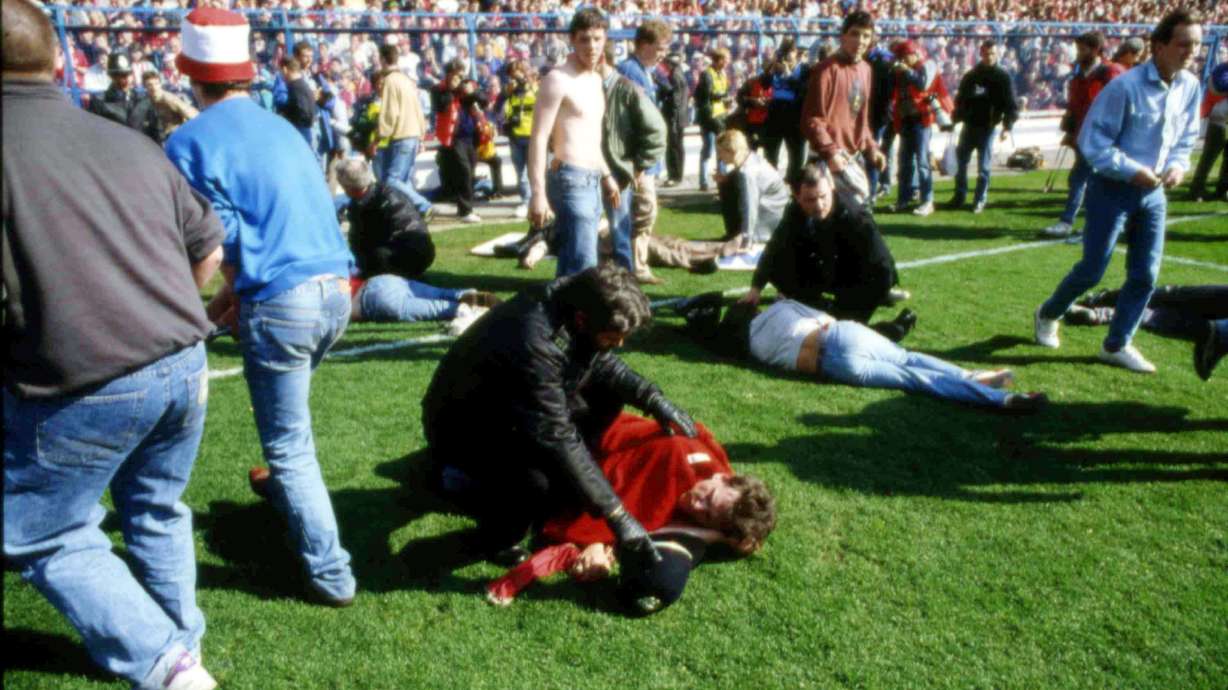 FILE - Stewards and supporters tend and care for wounded supporters on the field at Hillsborough Stadium, in Sheffield, England, April 15, 1989.