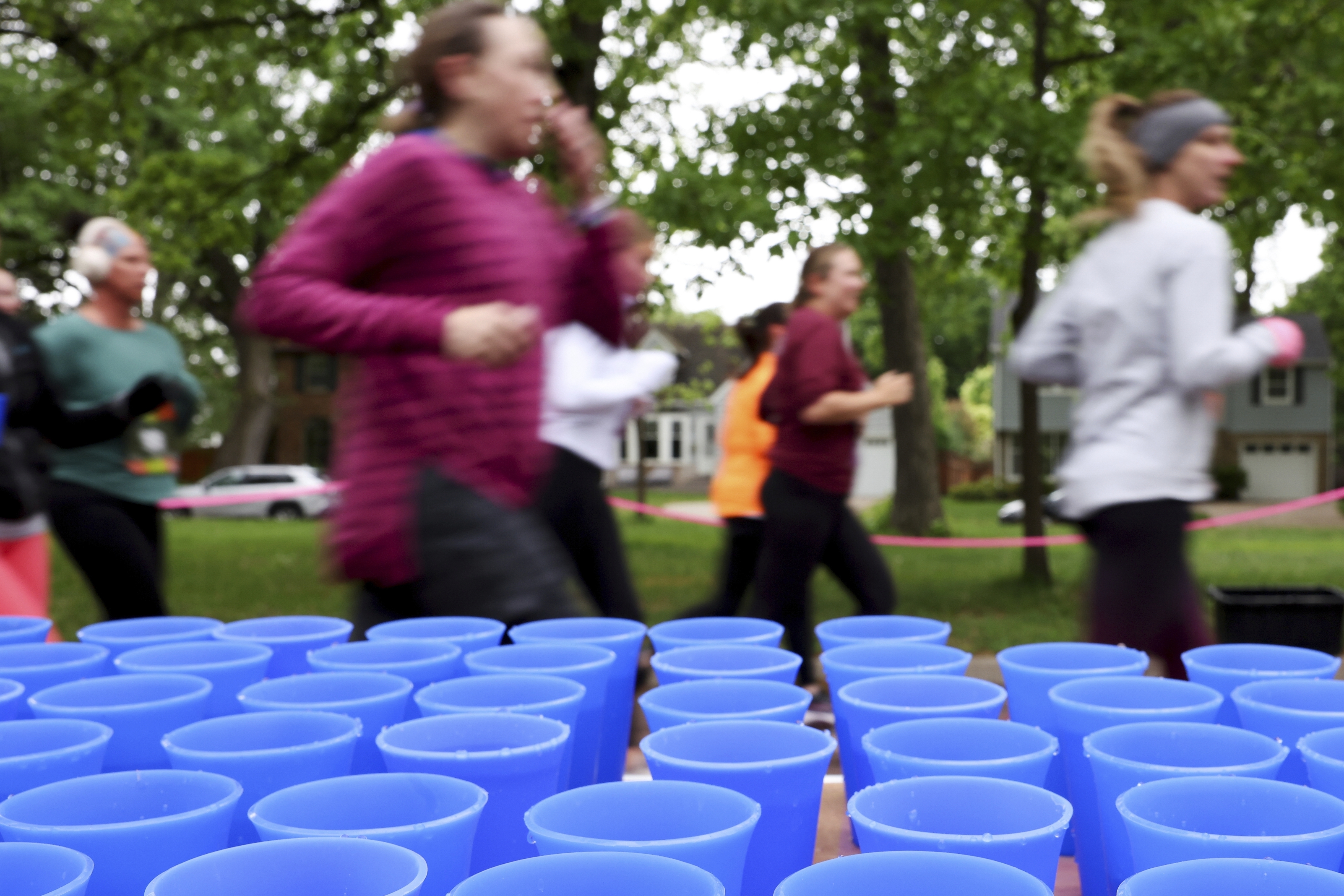 Runners pass a table with reusable silicone cups from Hiccup during the PNC Women Run the Cities race on Saturday, May 17, 2025, in Minneapolis. 