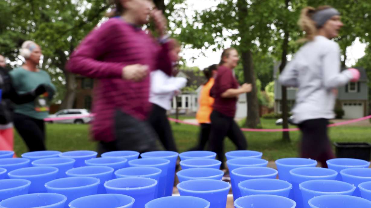 Runners pass a table with reusable silicone cups from Hiccup during the PNC Women Run the Cities race on Saturday, May 17, 2025, in Minneapolis.