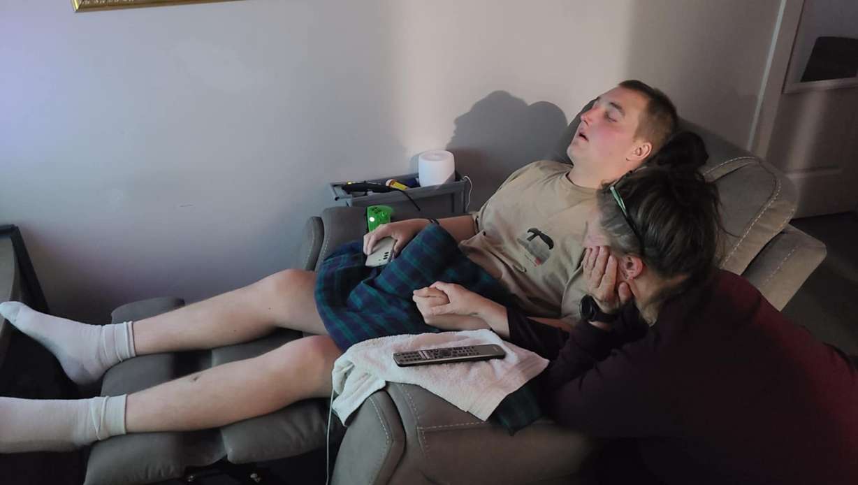 Lesli Groves, of Bountiful, holds the hand of her son, Roman Groves, who is fighting a losing battle at age 19 with Ewing sarcoma.