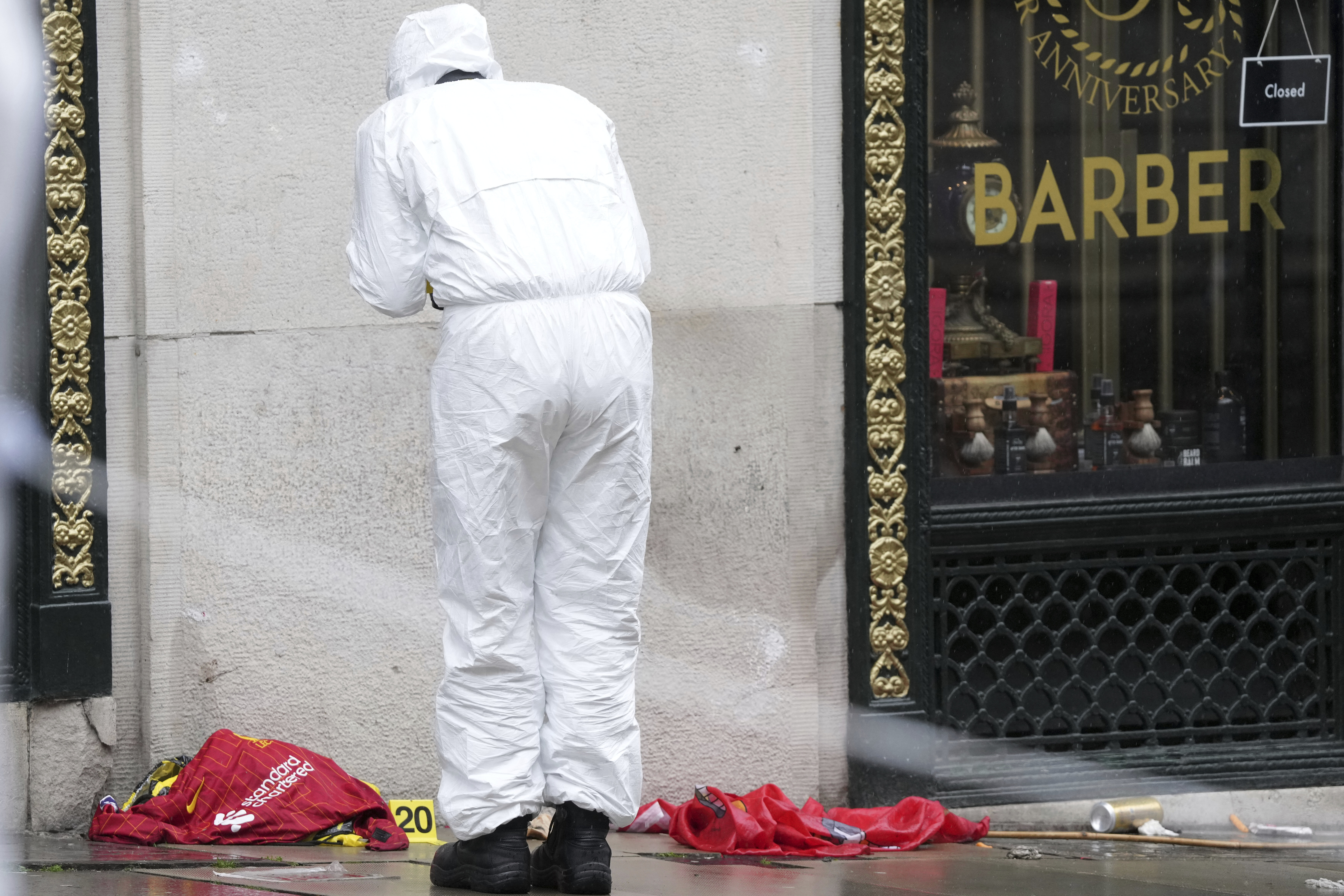 A Forensic officer looks at evidence near the site where a 53-year-old British man plowed a minivan into a crowd of Liverpool soccer fans who were celebrating the city's Premier League championship Monday, injuring more than 45 people in Liverpool, England, Tuesday, May 27, 2025.