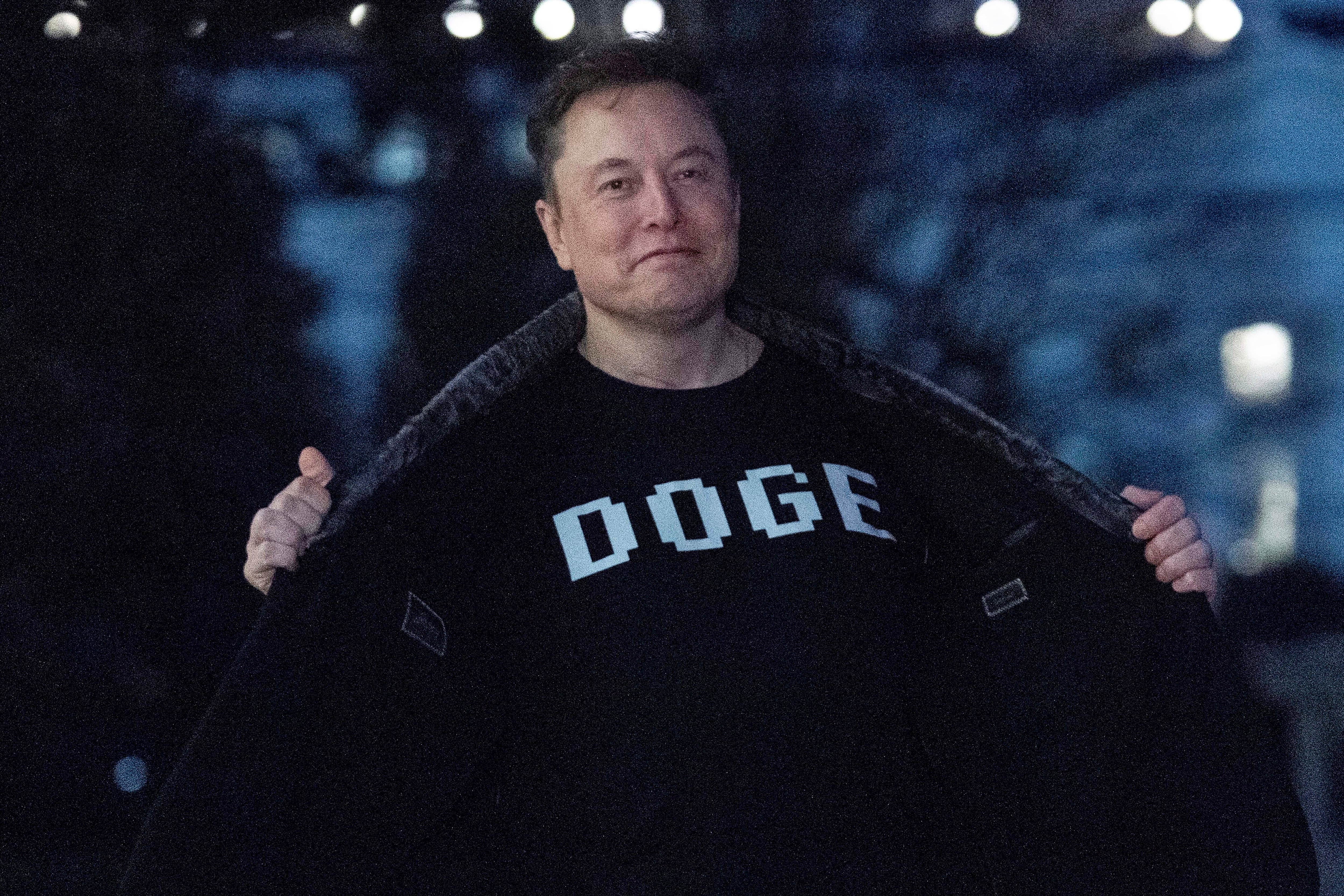 Elon Musk flashes his T-shirt that reads "DOGE" to the media as he walks on South Lawn of the White House, in Washington, March 9.