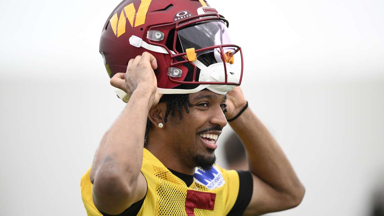 Washington Commanders quarterback Jayden Daniels puts on his helmet during NFL football practice, Wednesday, May 28, 2025, in Ashburn, Va.