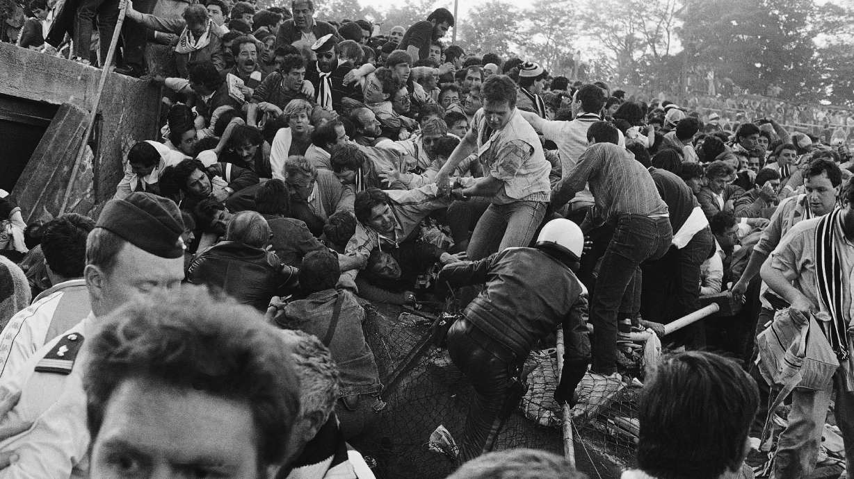 FILE - A crowd of soccer fans in the Brussels Heysel stadium, falls down in a heavy group over the broken fence just prior to the European Champion's Cup Final between Liverpool and Juventus of Turin, in Brussels, Belgium, May 29, 1985.