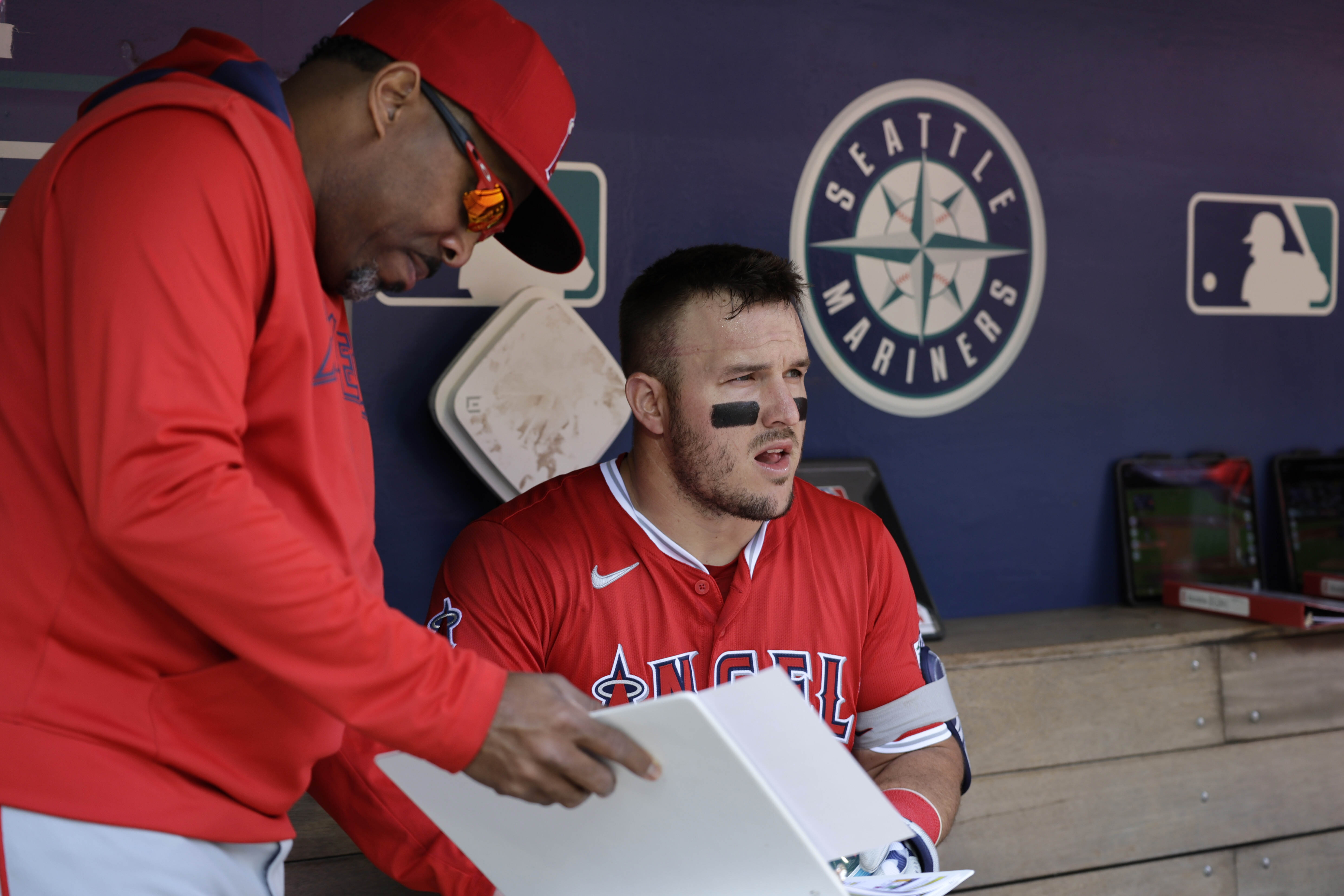 Los Angeles Angels' Mike Trout talks with batting coach Johnny Washington in the dugout before a baseball game against the Seattle Mariners, Wednesday, April 30, 2025, in Seattle. 