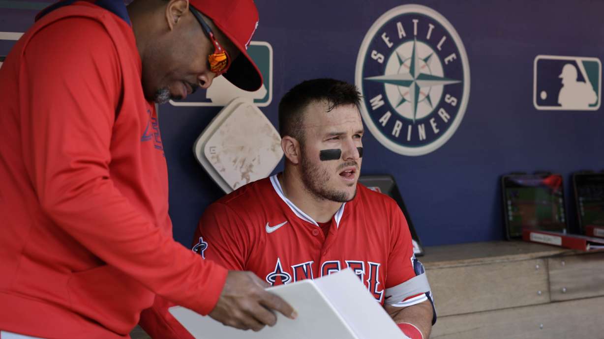 Los Angeles Angels' Mike Trout talks with batting coach Johnny Washington in the dugout before a baseball game against the Seattle Mariners, Wednesday, April 30, 2025, in Seattle.