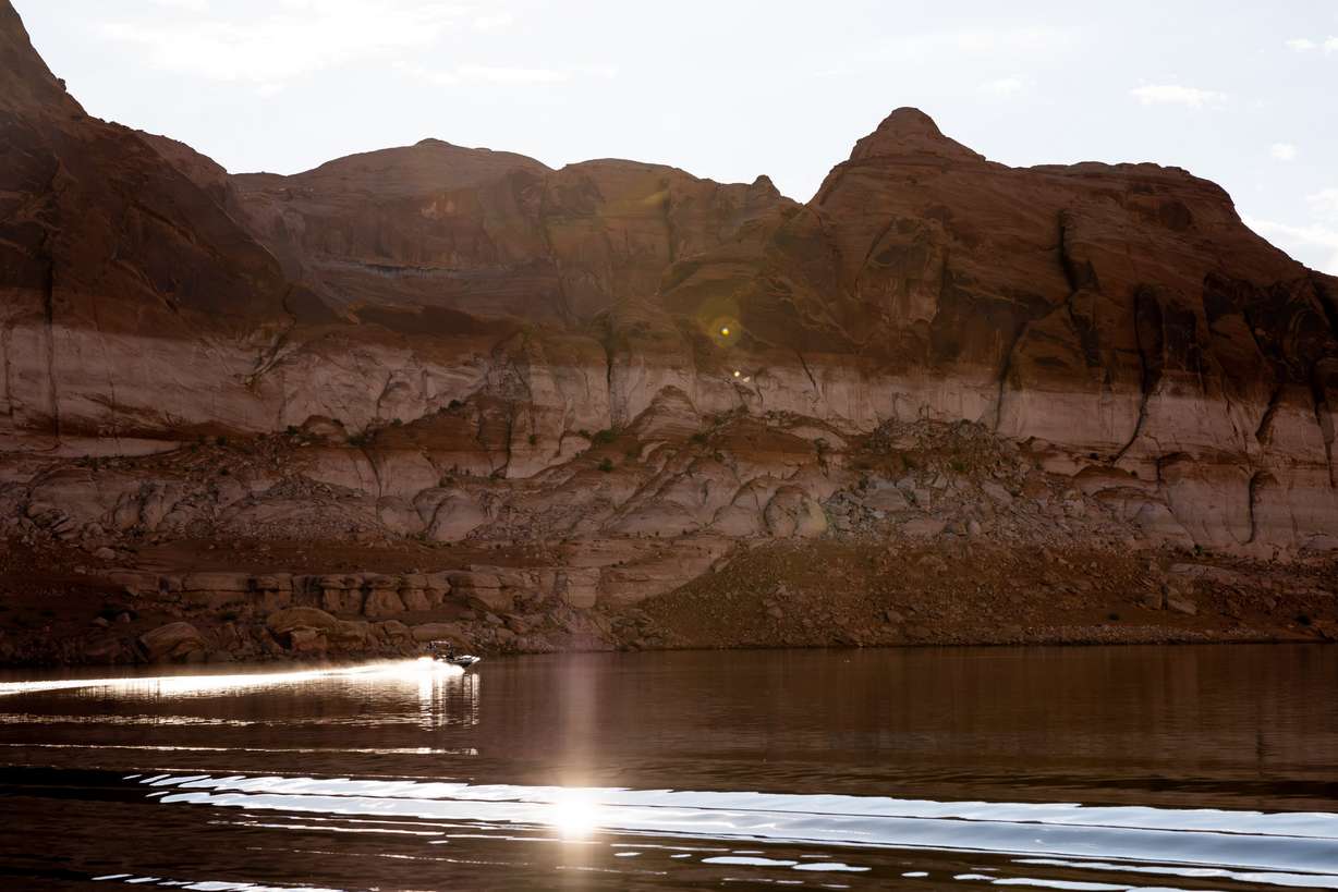 A boat is seen against the backdrop of Lake Powell’s “bathtub ring,” a light-colored coating of mineral deposits left on the canyon walls during periods of higher water in the reservoir, on Oct. 7, 2022, near Bullfrog.