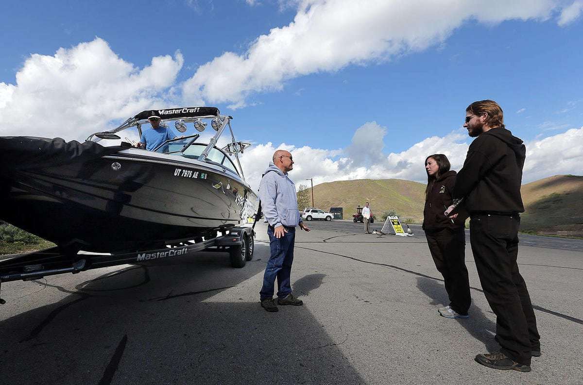 Division of Wildlife Resources quagga technicians Curtis Hutchinson, right, and Kaitlyn Winget discuss the quagga mussel decontamination process with Jeff Hammett as he arrives to boat at Deer Creek Reservoir, May 7, 2015.