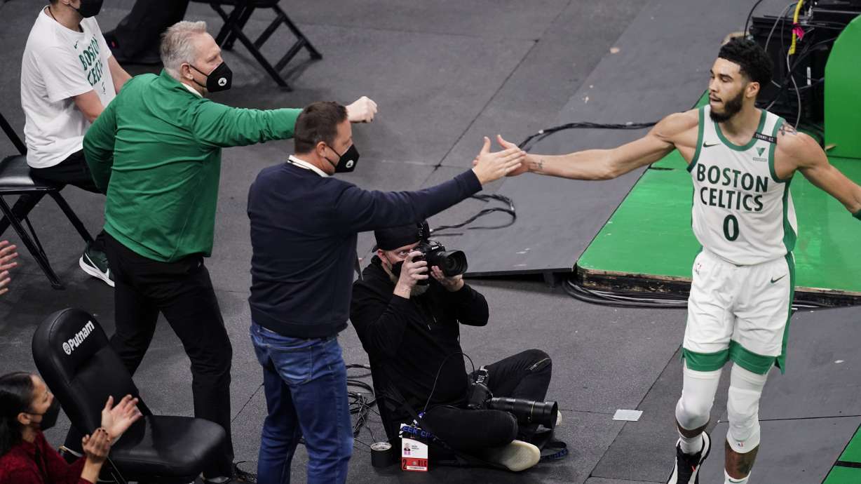 Boston Celtics forward Jayson Tatum (0) is congratulated by Celtics Assistant General Manager Austin Ainge, center, after scoring a basket during the first half of an NBA basketball game against the New Orleans Pelicans, Monday, March 29, 2021, in Boston. At left is Celtics President of Basketball Operations Danny Ainge, Austin's father.