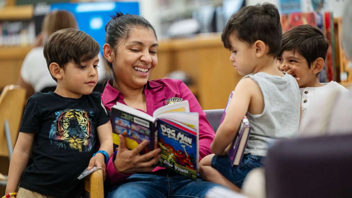 Darinka Cooper reads to her three sons Ilijah, Jeremiah and Isaiah Cooper as Taylorsville Library holds its summer reading kickoff party on May 30.