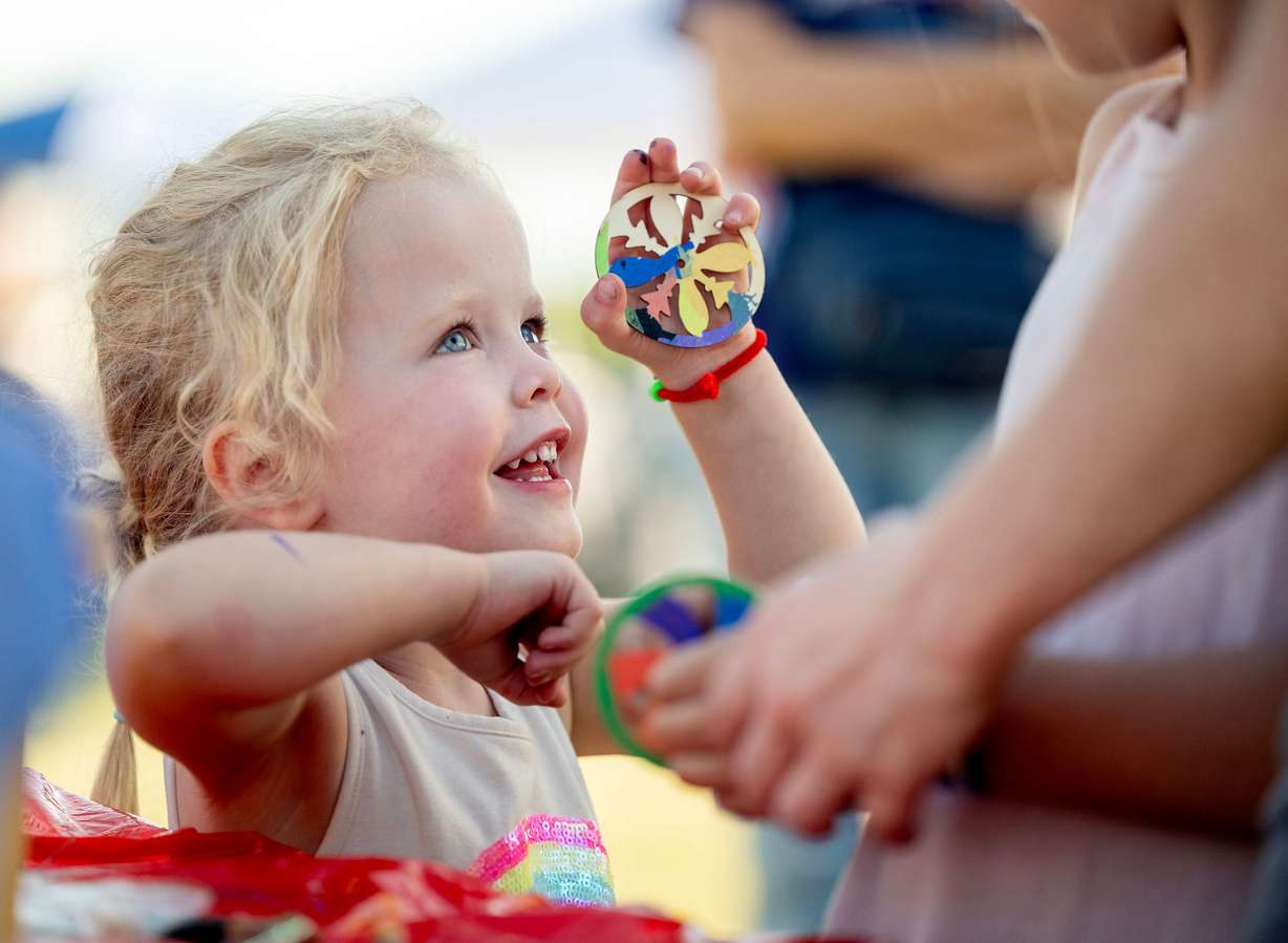 Nora Deklerk shows her wooden spinner to her mother, Kelsey Deklerk, as Taylorsville Library holds its summer reading kickoff party on May 30.