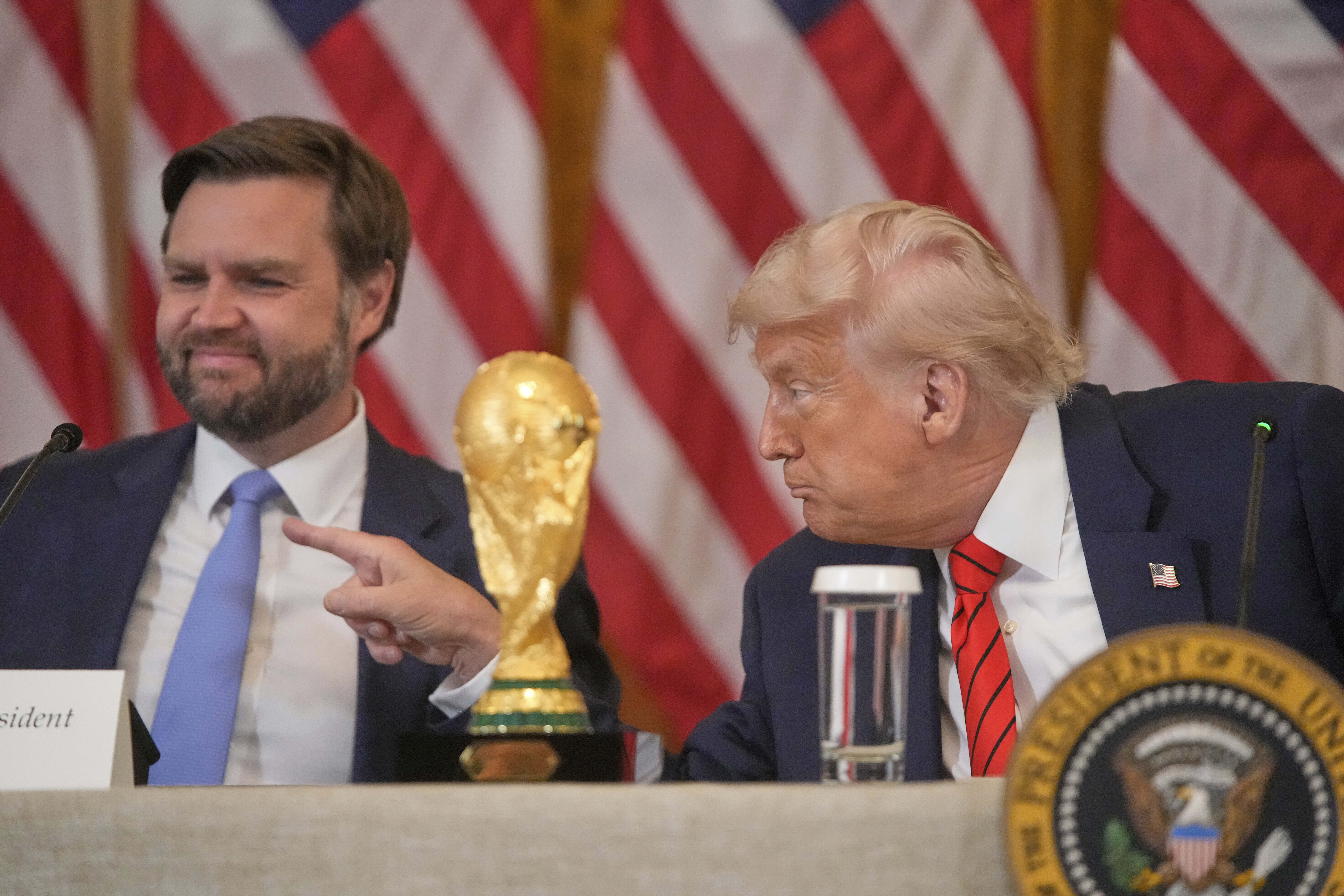 President Donald Trump gestures past Vice President JD Vance during a FIFA task force meeting on the 2026 FIFA World Cup in the East Room of the White House, Tuesday, May 6, 2025, in Washington. 