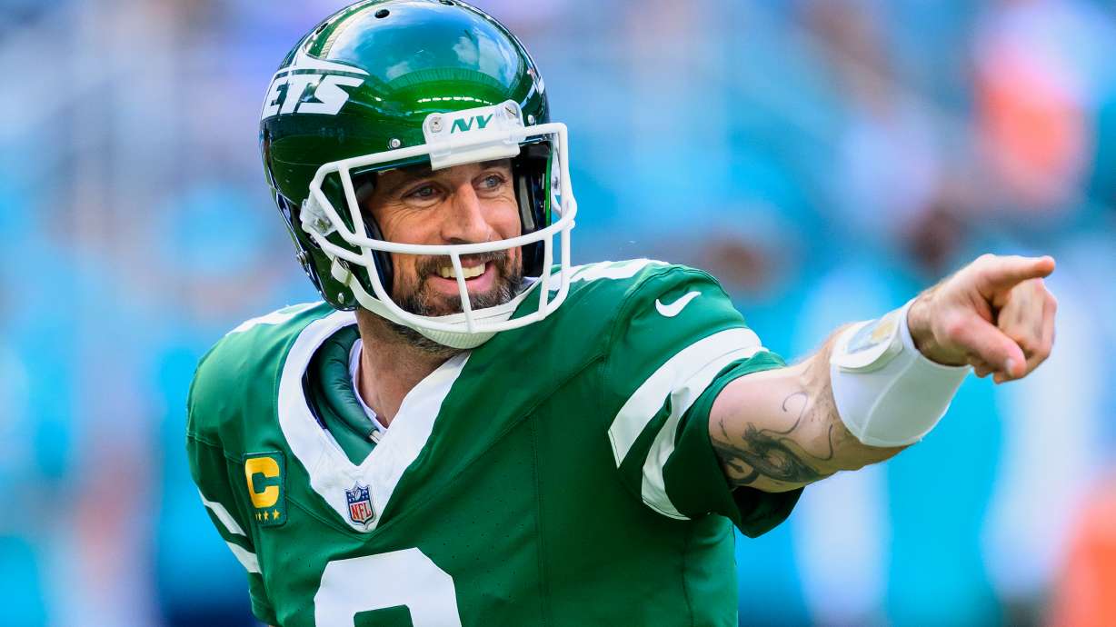 FILE - New York Jets quarterback Aaron Rodgers (8) smiles and points during an NFL football game against the Miami Dolphins, Sunday, Dec. 8, 2024, in Miami Gardens, Fla.