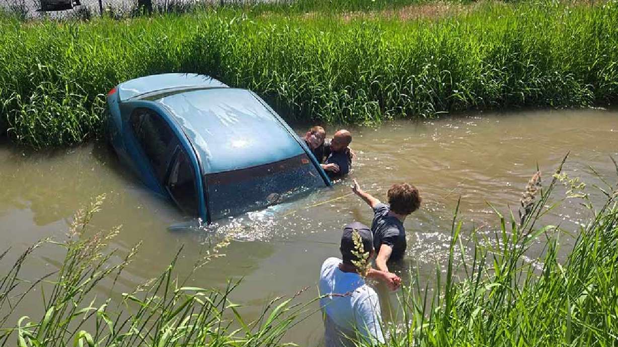 Three people work to rescue a woman from a canal in Pocatello, Idaho, Tuesday. The woman told Chubbuck police she was cut off by a black truck, causing her to veer into the canal.