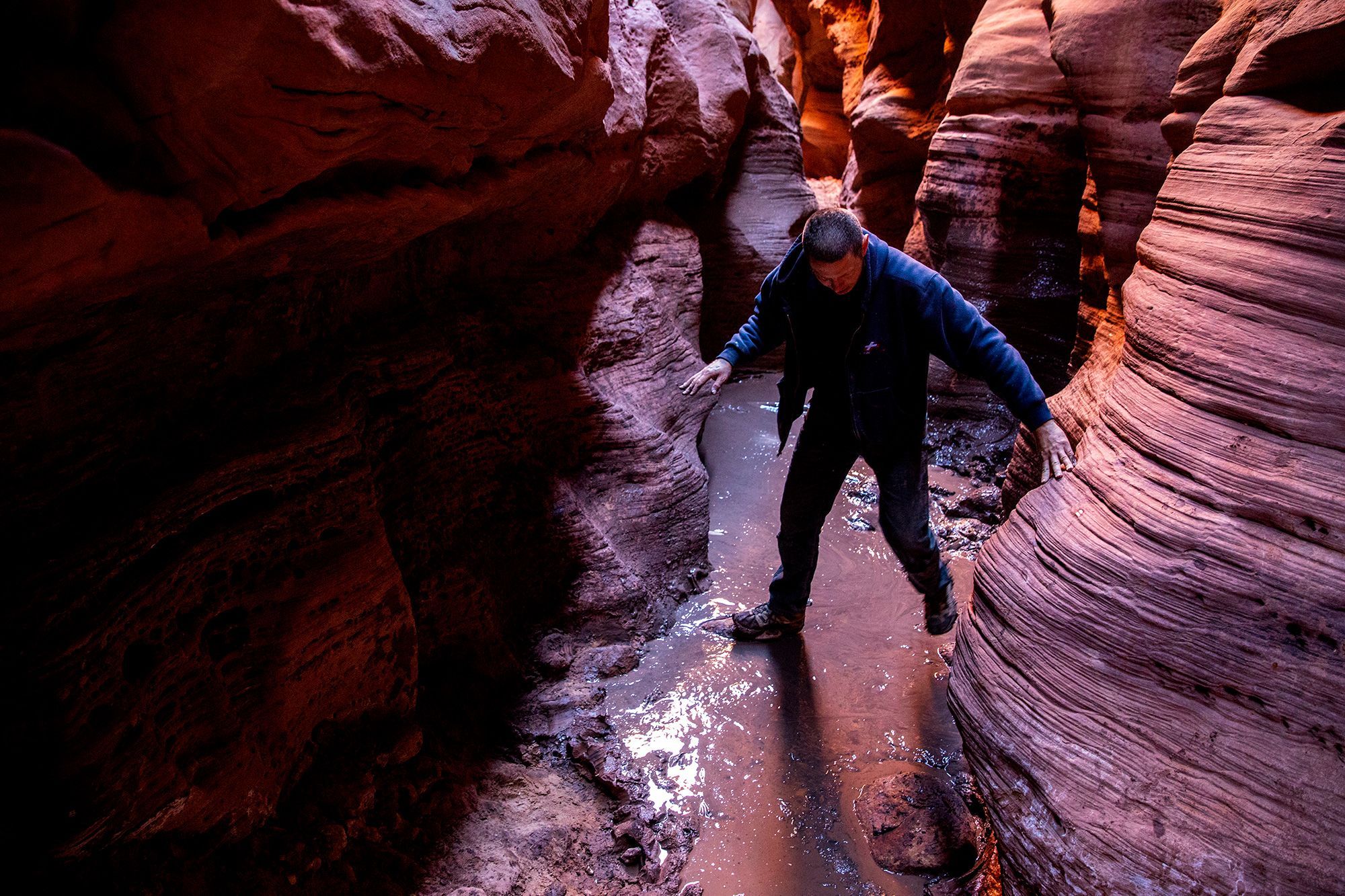 A hiker steps along rocks placed in a "cesspool," an obstacle known for its standing, putrid water, inside Buckskin Gulch near Kanab, Utah.