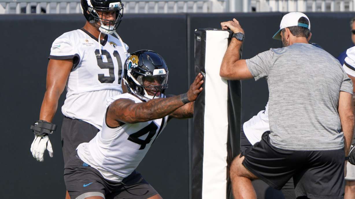 Jacksonville Jaguars defensive end Josh Hines-Allen, center, performs a drill as defensive end Arik Armstead (91) looks on during a team NFL football practice, Monday, June 2, 2025, in Jacksonville, Fla.