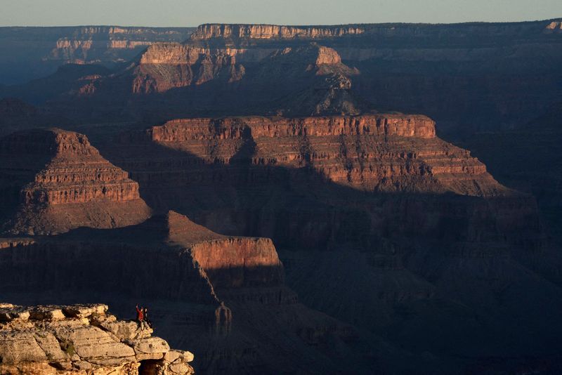 Tourists use their mobile phone while the early morning sunlight hits canyon ridges as seen from the south rim of Grand Canyon National Park near Tusayan, Ariz., May 16.