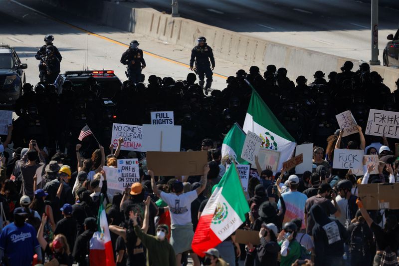 Demonstrators block the highway, as law enforcement officers stand facing them, during a protest against federal immigration sweeps in downtown Los Angeles, Calif., Sunday.
