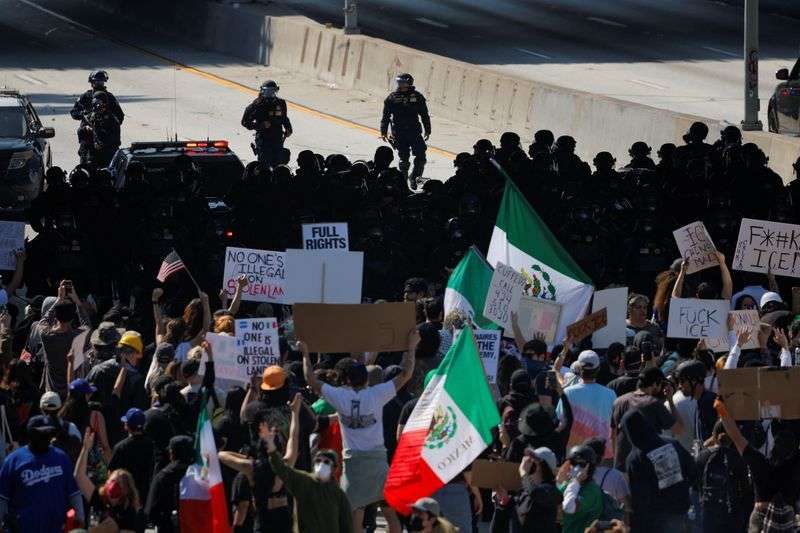 Demonstrators block the highway, as law enforcement officers stand facing them, during a protest against federal immigration sweeps in downtown Los Angeles, Calif., Sunday.