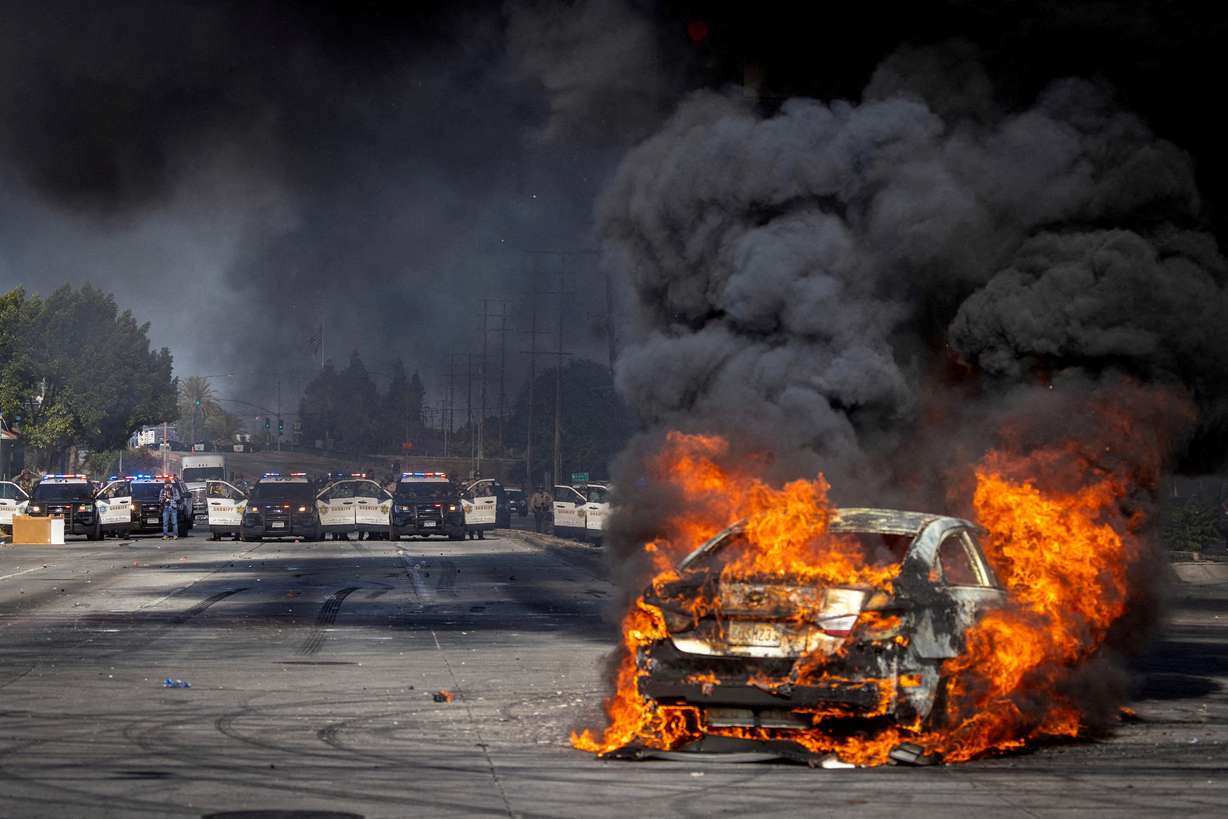 A car burns on Atlantic Boulevard during a standoff by protesters and law enforcement, following multiple detentions by Immigration and Customs Enforcement, in the Los Angeles County city of Compton, Calif., on Saturday.